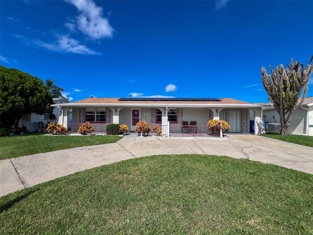 A single-story house with a concrete driveway, solar panels on the roof, and a front porch — 2349 HAMA DRIVE, HOLIDAY, FL