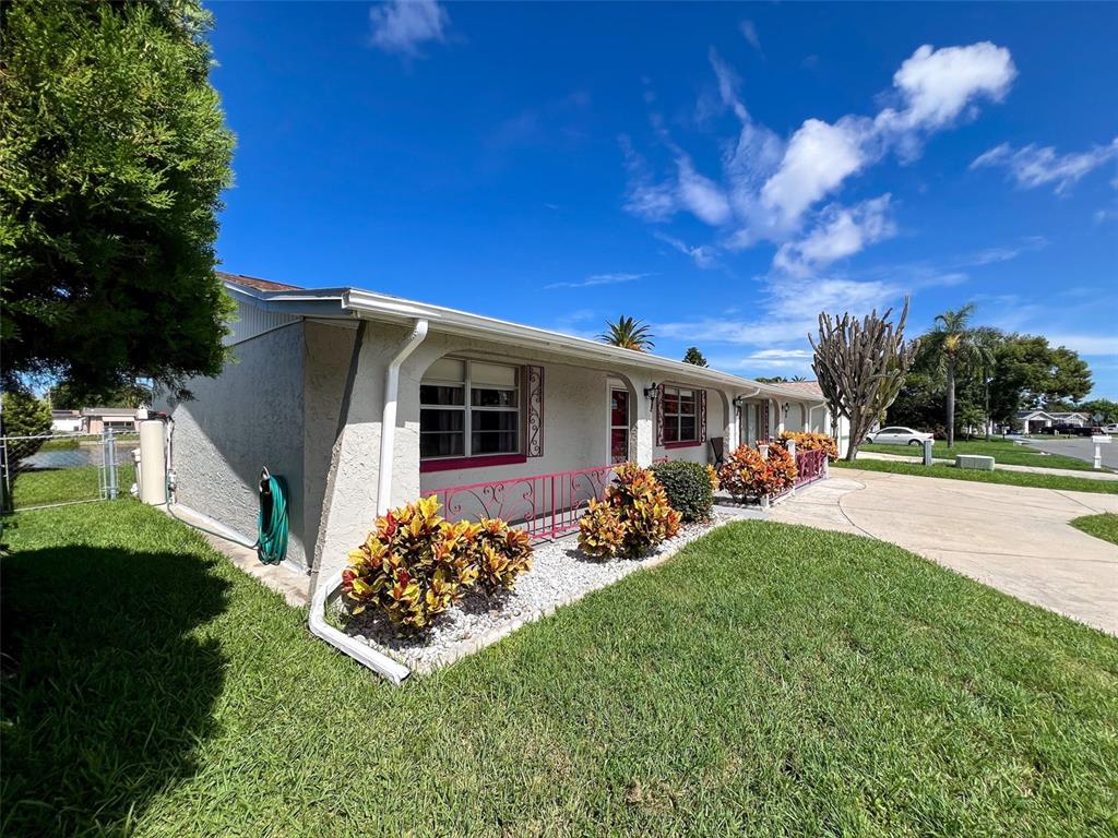 A single-story house with a white stucco exterior, pink metal railing, and landscaped front yard — 2349 HAMA DRIVE, HOLIDAY, FL