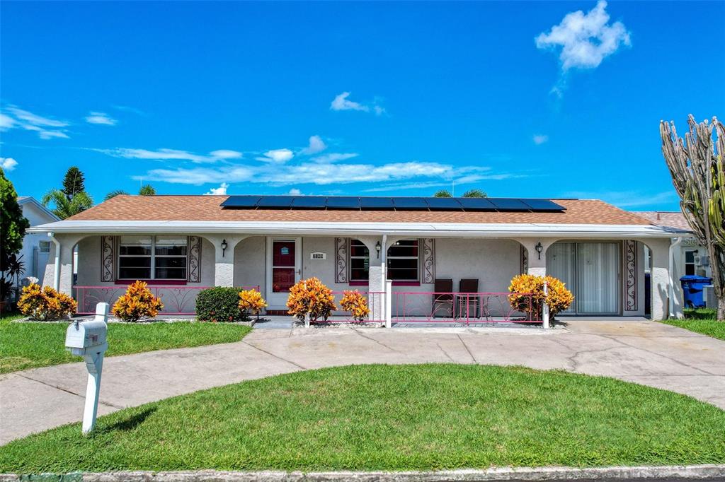 A single-story house with a brown roof, solar panels, and a front porch with pink railings — 2349 HAMA DRIVE, HOLIDAY, FL