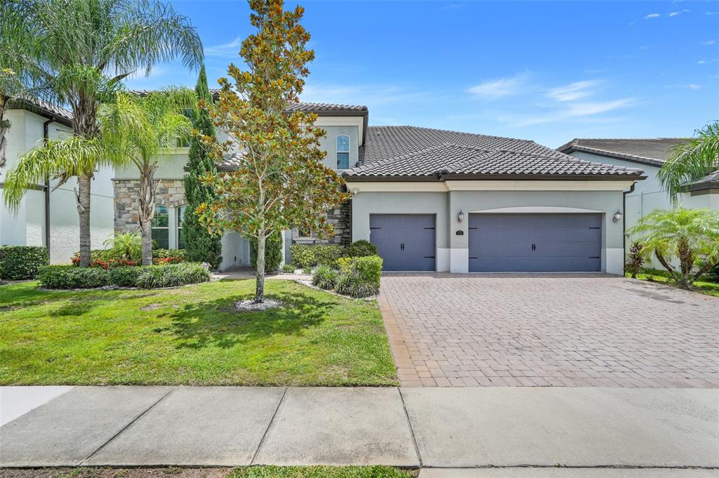 A two-story house with a stone facade, a three-car garage, and a paved driveway — 7920 CHILTON DRIVE, ORLANDO, FL