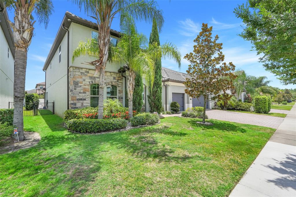 A two-story house with a stone facade, palm trees, and a paved driveway — 7920 CHILTON DRIVE, ORLANDO, FL