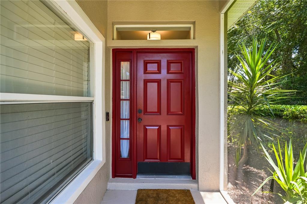 A red front door with a side window and a transom light under a porch — 4228 SILVER STAR DRIVE, SPRING HILL, FL