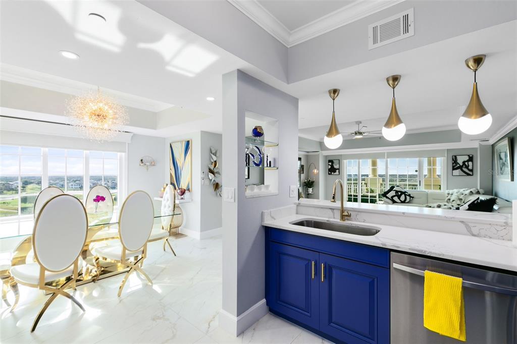 A kitchen with blue cabinets and a sink overlooks a dining area with gold chairs — 7593 GATHERING DRIVE UNIT 802, REUNION, FL