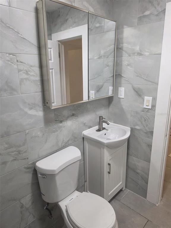 A small bathroom features a white pedestal sink, a toilet, and a mirrored medicine cabinet — 1844 JOHN RIVERS STREET UNIT N, SARASOTA, FL