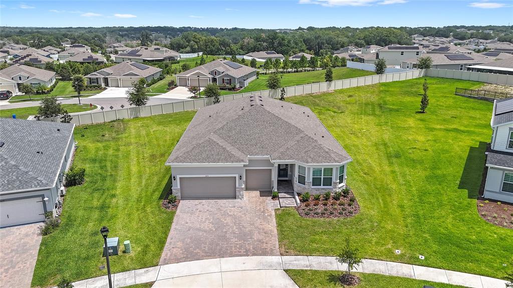 An aerial view shows a single-story suburban house with a paved driveway and large lawn — 5173 FOOTHILLS PRESERVE LOOP, MOUNT DORA, FL