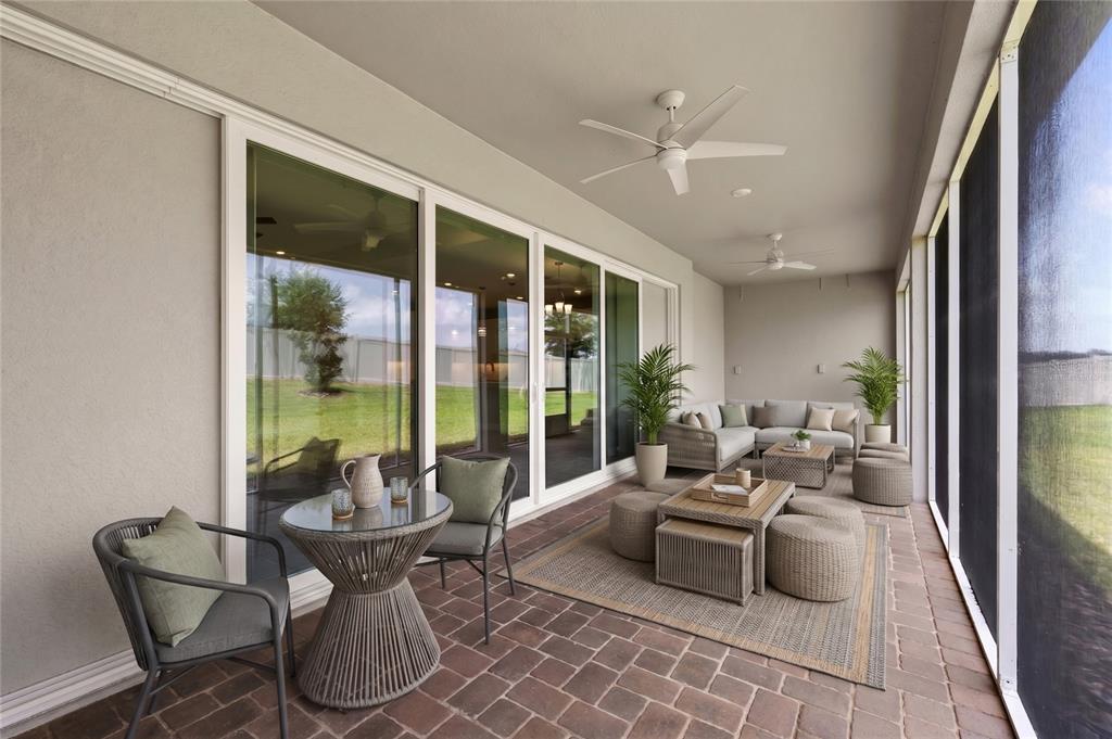 A covered patio features brick flooring, outdoor furniture, and large sliding glass doors — 5173 FOOTHILLS PRESERVE LOOP, MOUNT DORA, FL