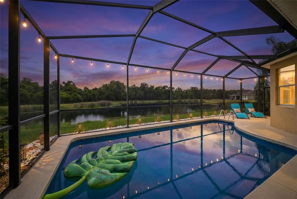 A living room with a large sectional sofa, television, and dining area overlooking a pool — 12287 LAVENDER LOOP, BRADENTON, FL