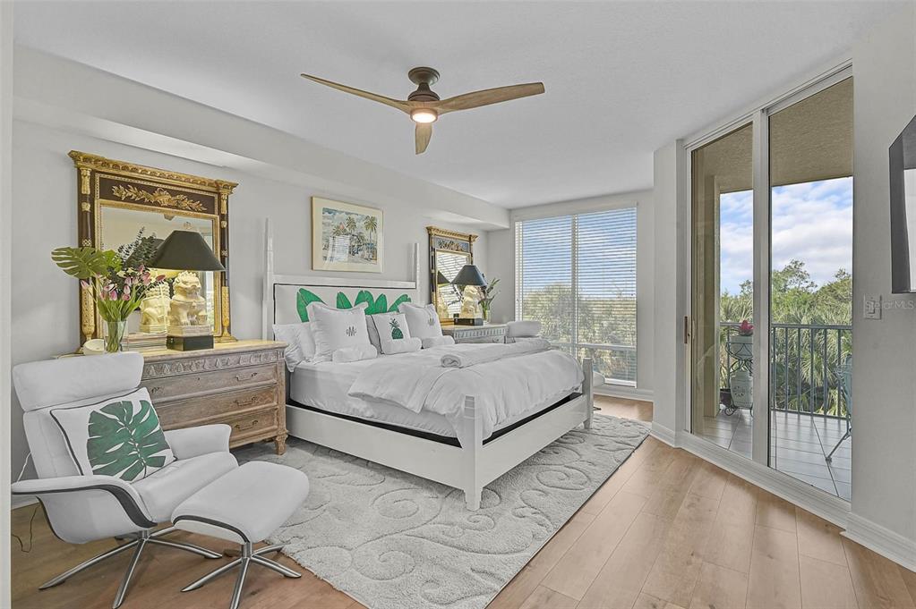 A bedroom features a white bed, a lounge chair, and a balcony with outdoor views — 385 N POINT ROAD UNIT 304, OSPREY, FL
