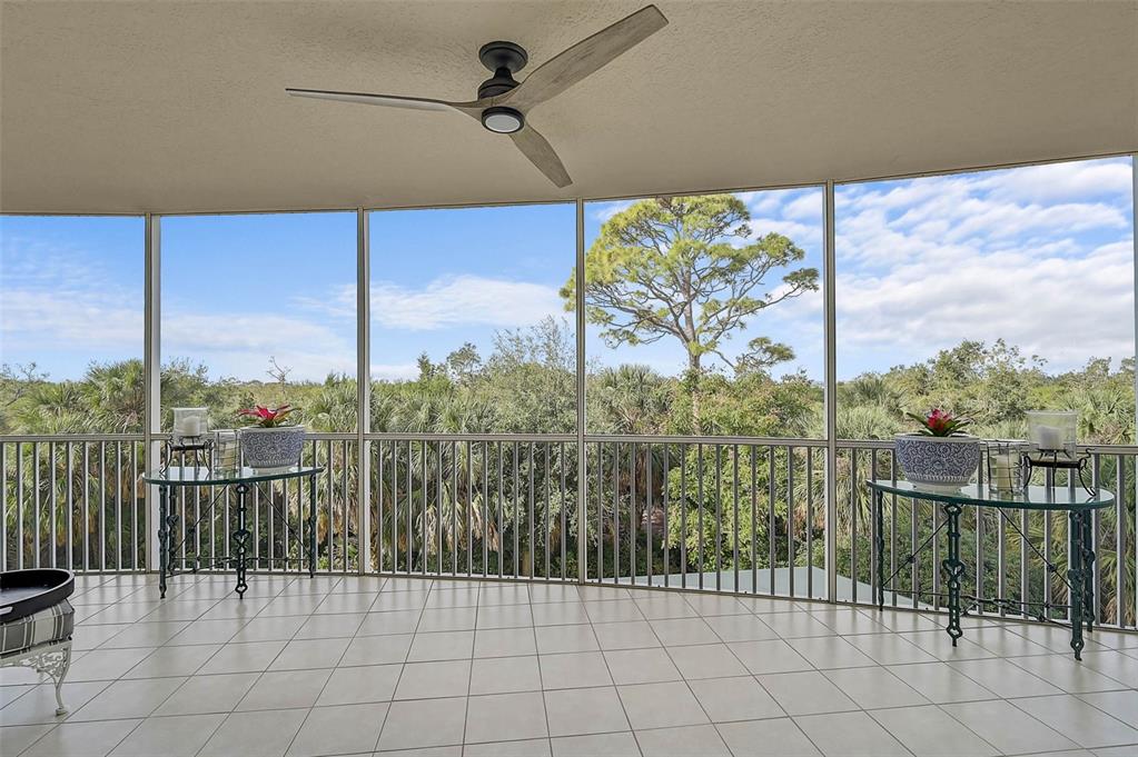 A screened-in balcony features tiled flooring, a ceiling fan, and views of surrounding trees — 385 N POINT ROAD UNIT 304, OSPREY, FL