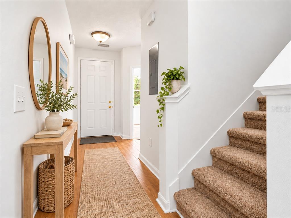 An entryway features light blue walls, wood-look tile flooring, and a carpeted staircase — 7631 LONG ISLAND DR, KISSIMMEE, FL