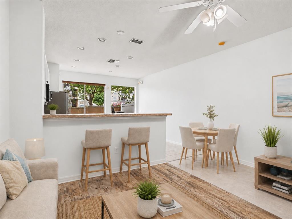 A room with light blue walls, wood-look flooring, a breakfast bar, and a ceiling fan — 7631 LONG ISLAND DR, KISSIMMEE, FL