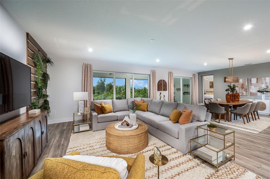 A living room features a large gray sectional, a round woven coffee table, and wood flooring — 18607 ARBOR VISTA DRIVE, VENICE, FL