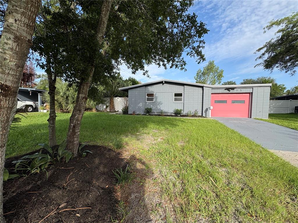 A gray single-story house with a red garage door sits on a grassy lot — 885 CARNATION DRIVE, WINTER PARK, FL