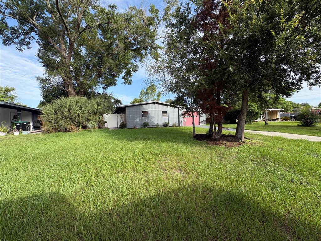A gray single-story house sits behind a large grassy yard with mature trees — 885 CARNATION DRIVE, WINTER PARK, FL