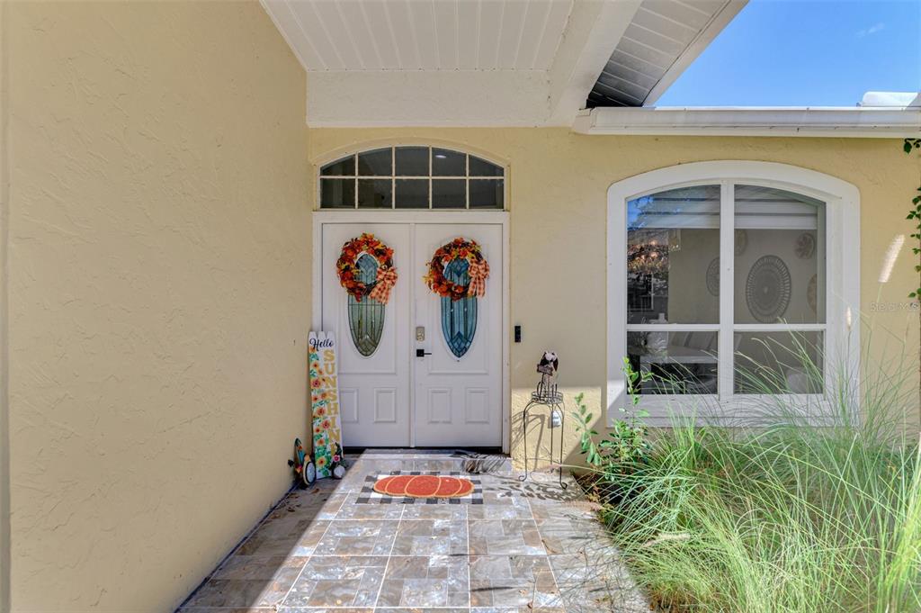 A front entryway features double doors with decorative wreaths, a tiled porch, and a large window — 583 PINE RANCH EAST ROAD, OSPREY, FL