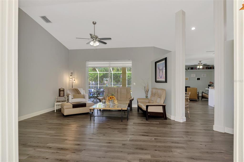 A living room with gray walls, wood-look flooring, a ceiling fan, and sliding glass doors — 583 PINE RANCH EAST ROAD, OSPREY, FL