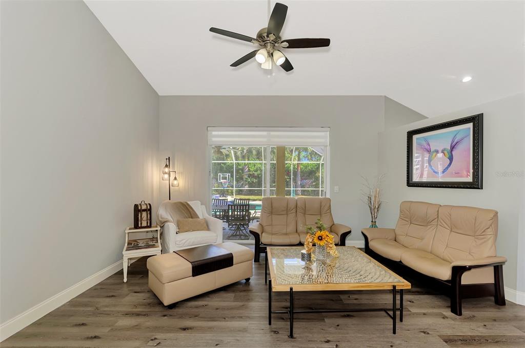 A living room features light gray walls, wood-look flooring, a ceiling fan, and patio access — 583 PINE RANCH EAST ROAD, OSPREY, FL