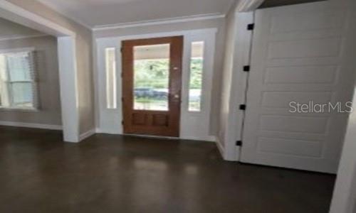 An entryway features a wooden front door with sidelights, white trim, and polished concrete floors — 3355 SCHOOLHOUSE ROAD, HARMONY, FL