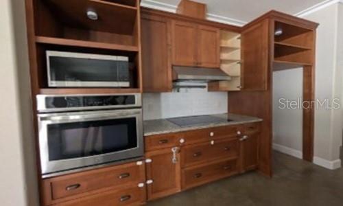 A kitchen features wood cabinets, stainless steel appliances, and a built-in microwave and oven unit — 3355 SCHOOLHOUSE ROAD, HARMONY, FL