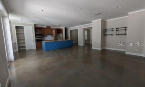 An open-concept kitchen with a blue island and concrete floors overlooks a spacious living area — 3355 SCHOOLHOUSE ROAD, HARMONY, FL