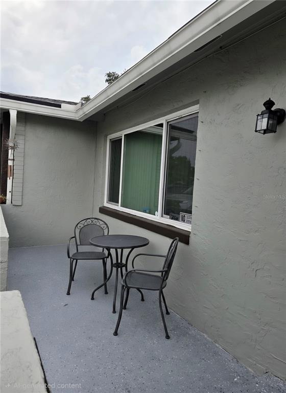 A small patio with a metal table and two chairs sits against a gray house — 2245 ELIZABETH DRIVE, BRANDON, FL