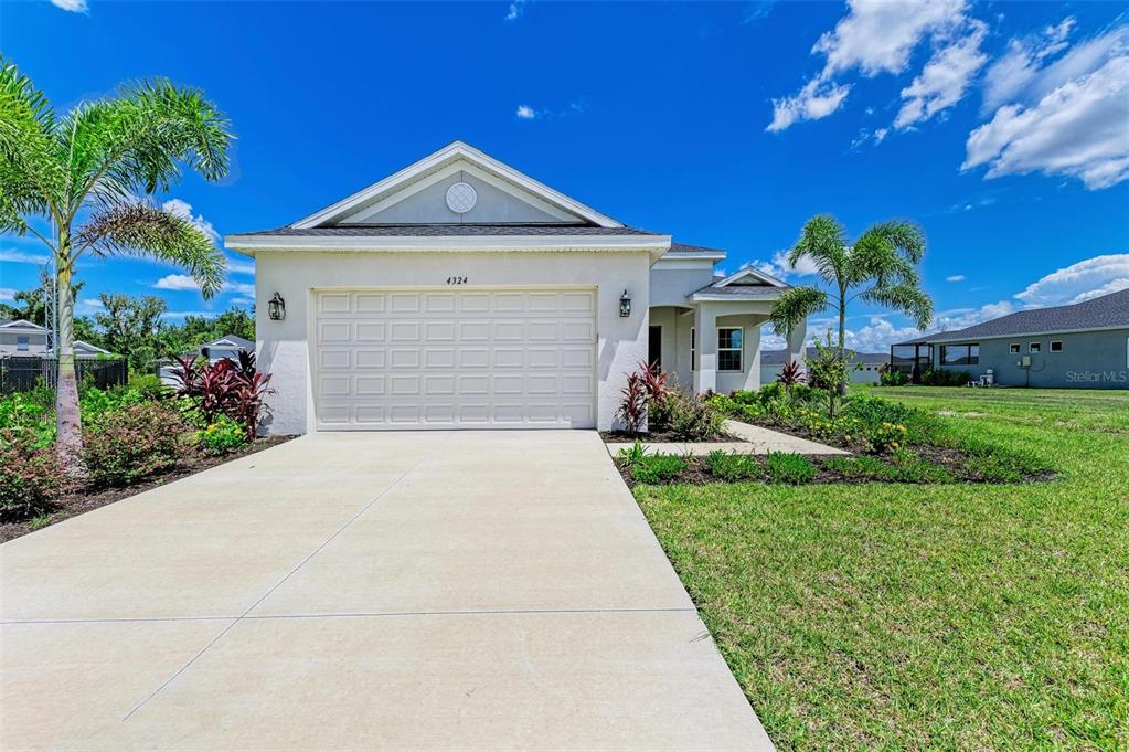 A single-story house with a white stucco exterior, a two-car garage, and palm trees — 4324 SEA MARSH PLACE, PARRISH, FL