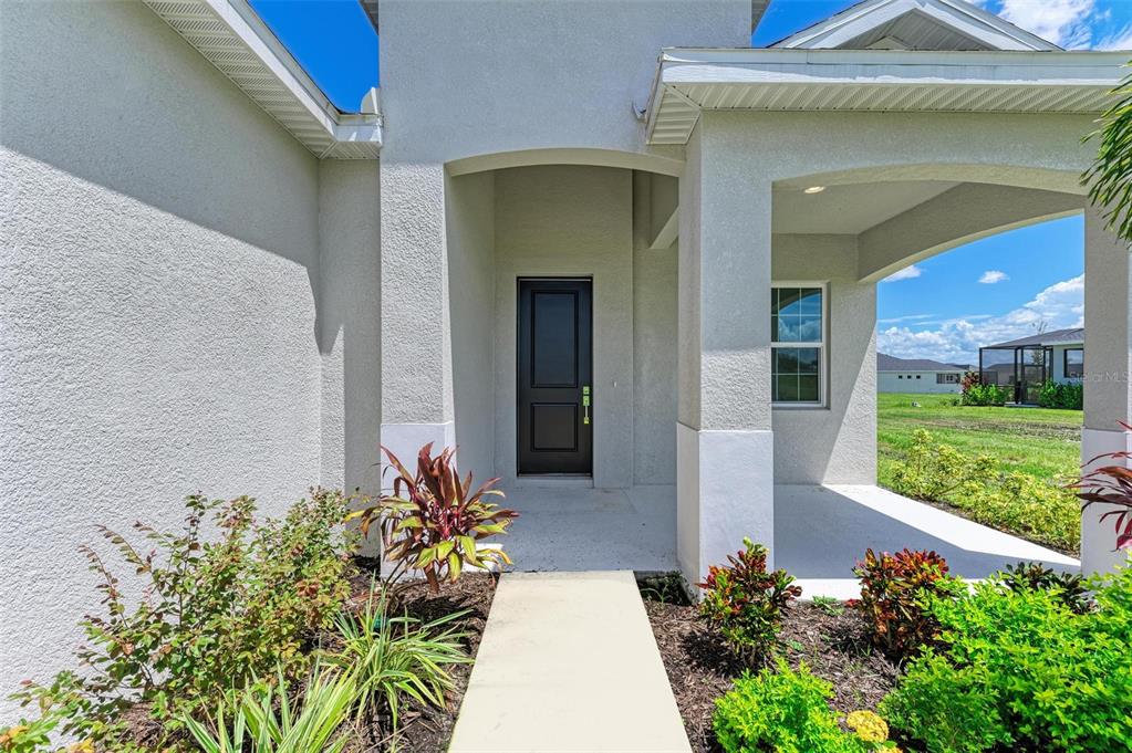 A concrete walkway leads to the covered front entrance of a light-colored stucco house — 4324 SEA MARSH PLACE, PARRISH, FL