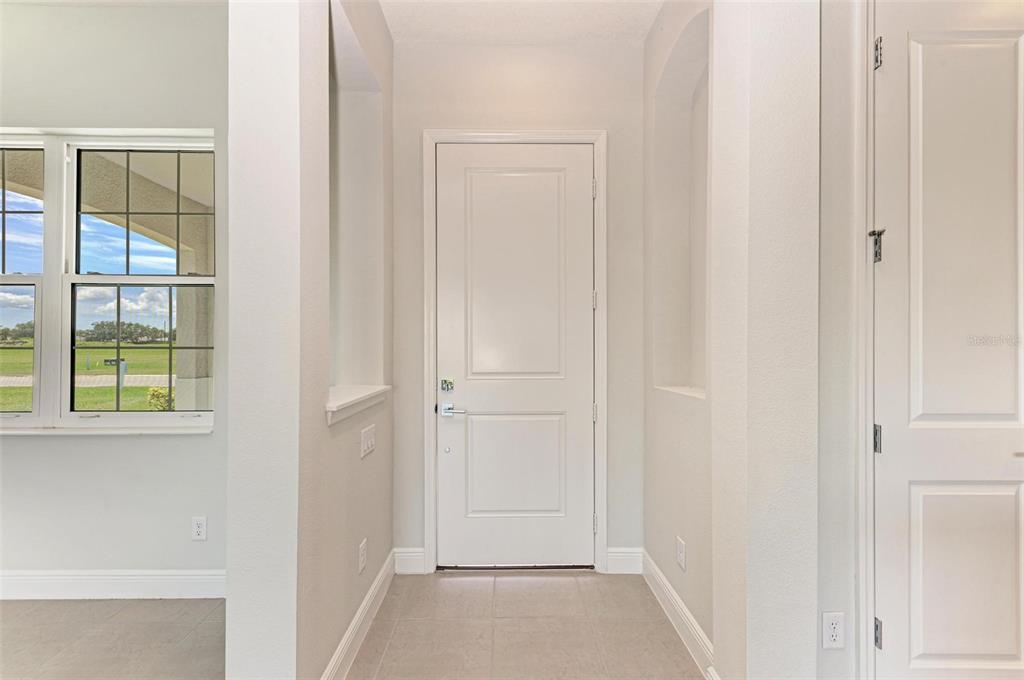 A white front door is centered in a tiled entryway with recessed wall niches — 4324 SEA MARSH PLACE, PARRISH, FL
