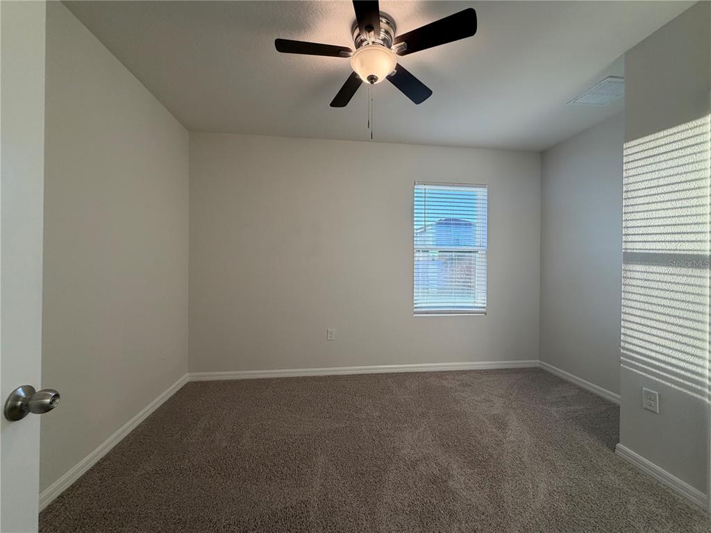 An empty bedroom features neutral walls, gray carpeting, a ceiling fan, and a window — 16805 TRITE BEND STREET, WIMAUMA, FL