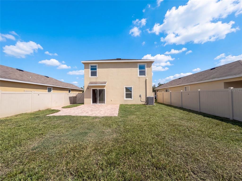 The exterior rear view of a two-story house features a paved patio and fenced yard — 16805 TRITE BEND STREET, WIMAUMA, FL