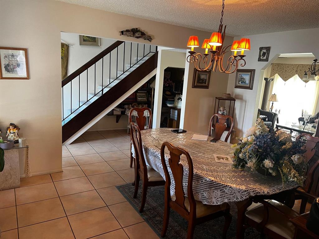 A dining room with a wooden table, chairs, chandelier, and a staircase in the background — 7804 SNOWBERRY CIRCLE, ORLANDO, FL