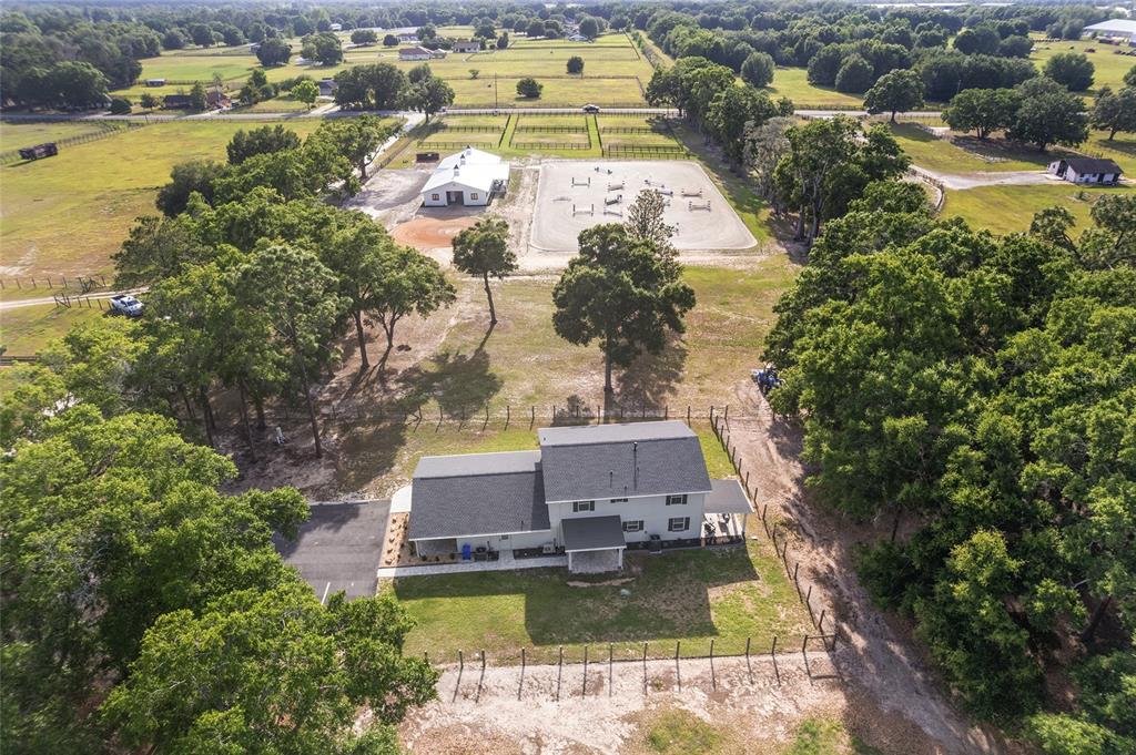 An aerial view shows a two-story house, a barn, and a riding arena on land — 663 NW 80TH AVENUE, OCALA, FL
