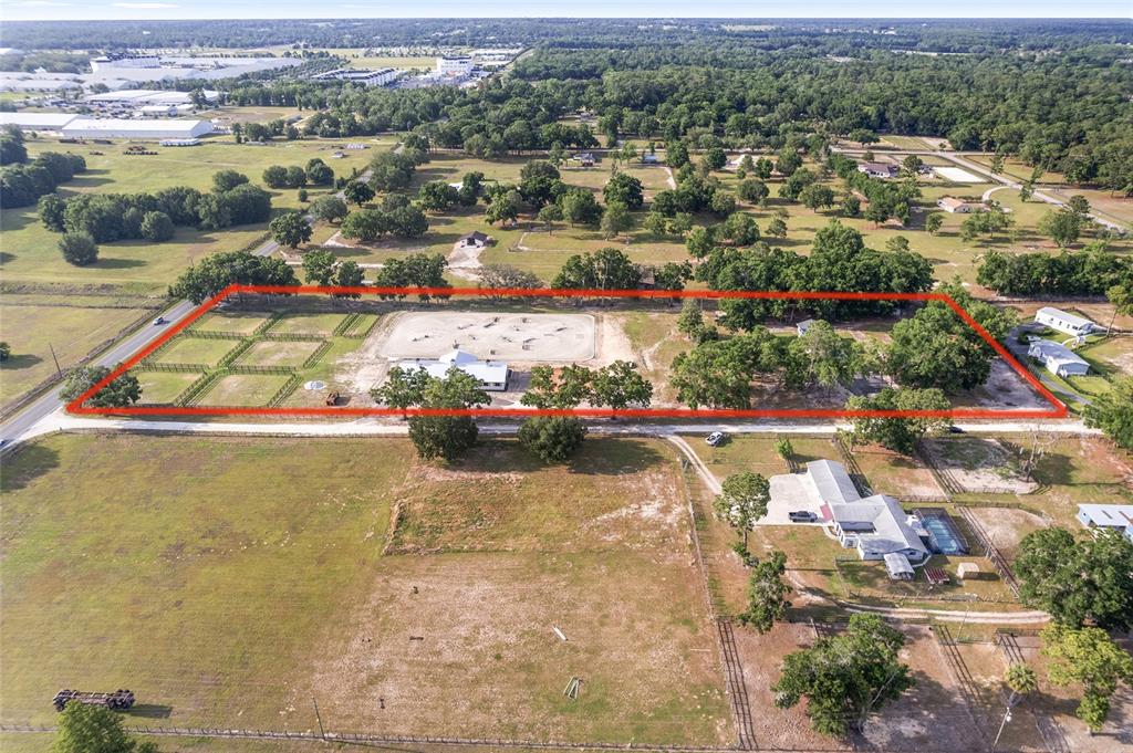 An aerial view shows a fenced equestrian property with a riding arena and several buildings — 663 NW 80TH AVENUE, OCALA, FL