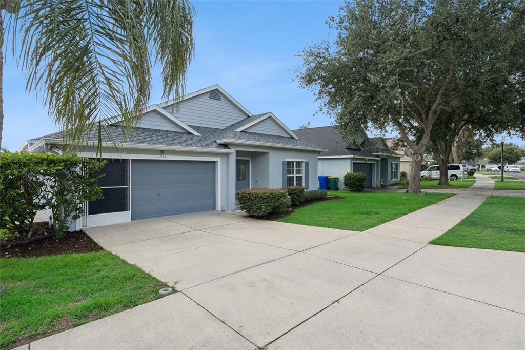 A single-story house with a gray garage, light siding, and a concrete driveway — 1324 KELLOGG DRIVE, TAVARES, FL
