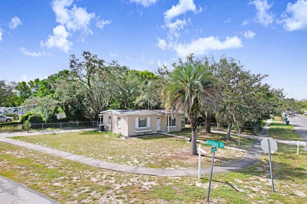 A single-story house with a palm tree in the front yard at a street corner — 1228 ACADEMY AVENUE, SPRING HILL, FL