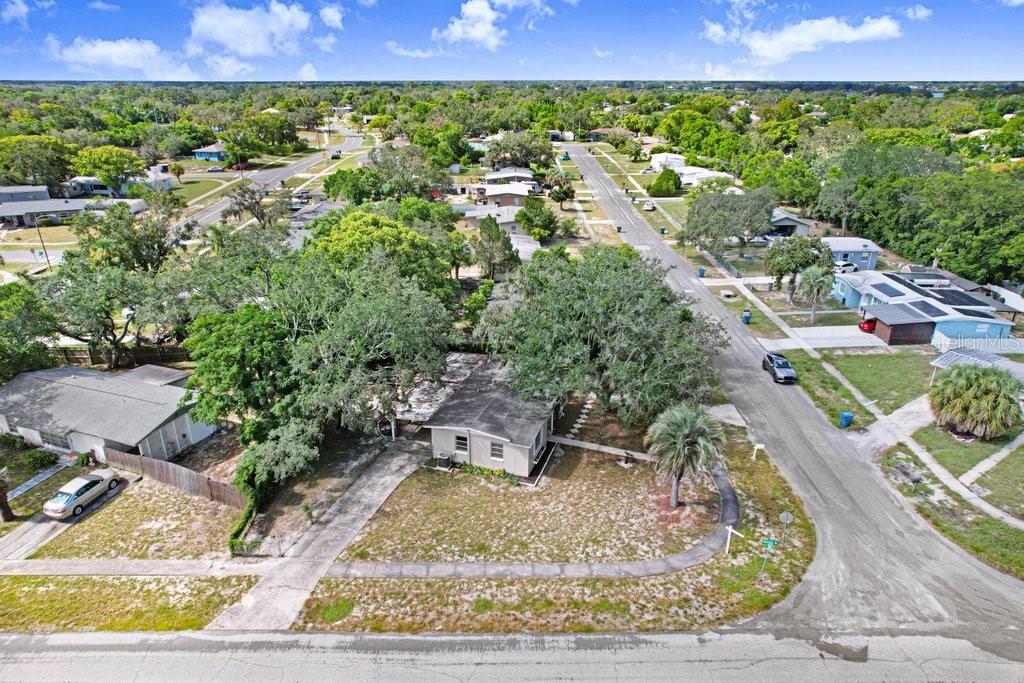 An aerial view shows a single-story house with a flat roof on a corner lot — 1228 ACADEMY AVENUE, SPRING HILL, FL