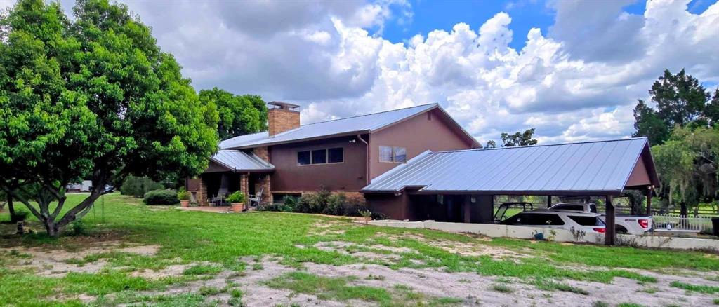 A brown house with a metal roof and an attached carport sits on a lawn — 5757 TRASK ROAD, FORT MEADE, FL