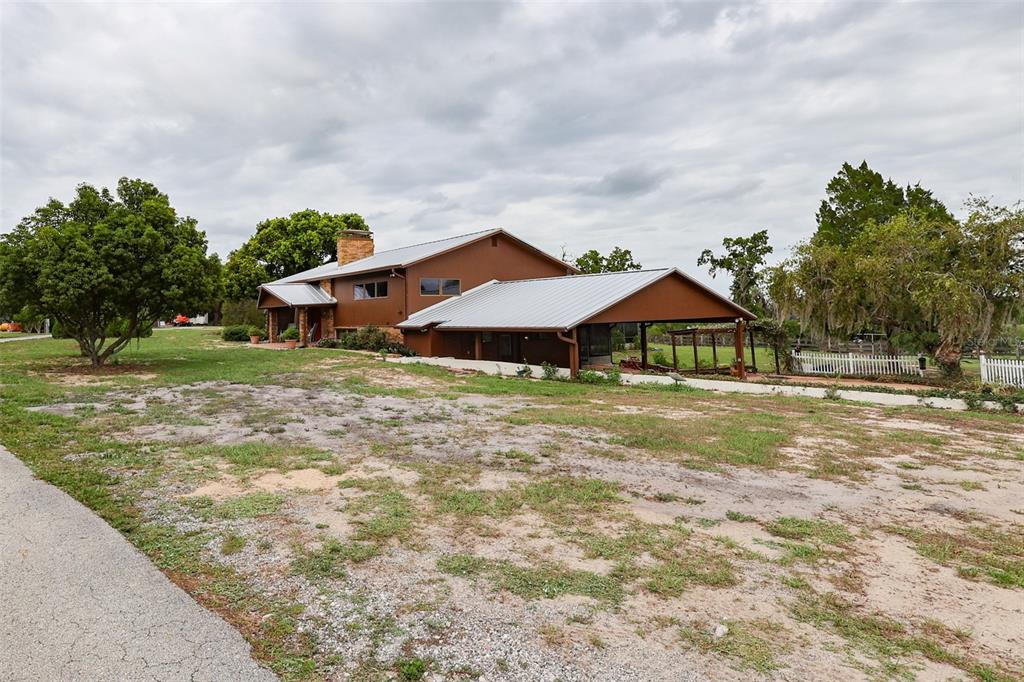 A brown two-story house with a metal roof and an attached carport sits on land — 5757 TRASK ROAD, FORT MEADE, FL