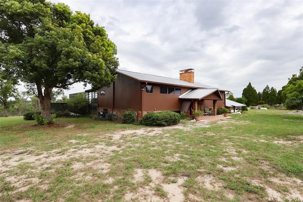 A brown house with a metal roof and brick chimney sits on a grassy lot — 5757 TRASK ROAD, FORT MEADE, FL