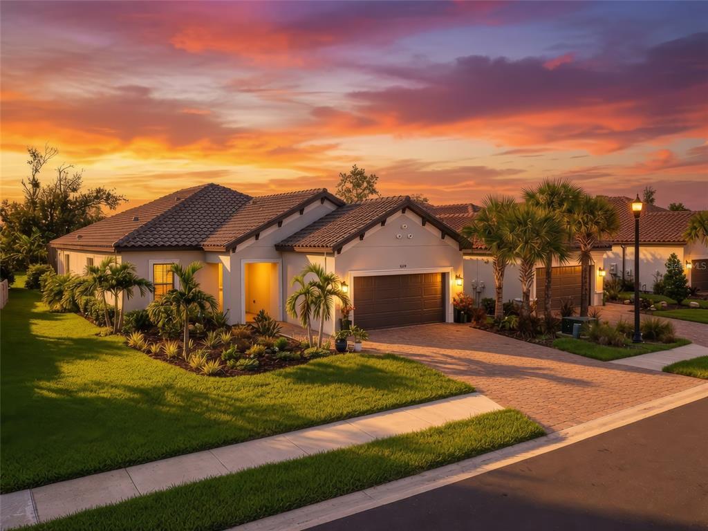 A single-story house with a tiled roof, garage, and landscaped yard under a sunset sky — 5119 CASERTA COURT, PALMETTO, FL