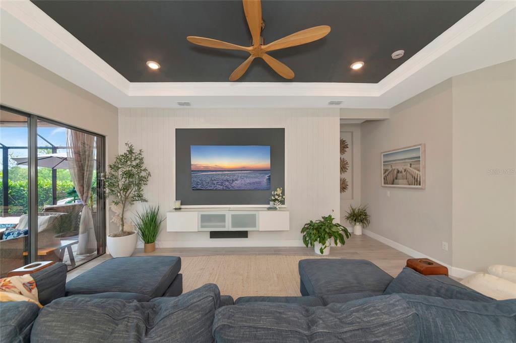 A living room features a dark tray ceiling, a wall-mounted television, and a blue sectional sofa — 5119 CASERTA COURT, PALMETTO, FL