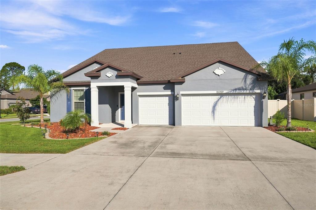A single-story house with a gray exterior, a two-car garage, and a concrete driveway — 18359 CORTES CREEK BOULEVARD, SPRING HILL, FL