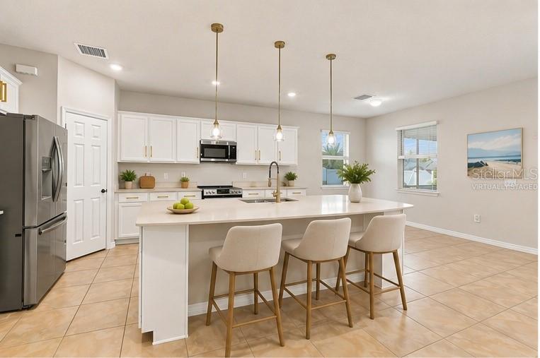 A kitchen with white cabinets, a large island with three stools, and tile flooring — 18359 CORTES CREEK BOULEVARD, SPRING HILL, FL