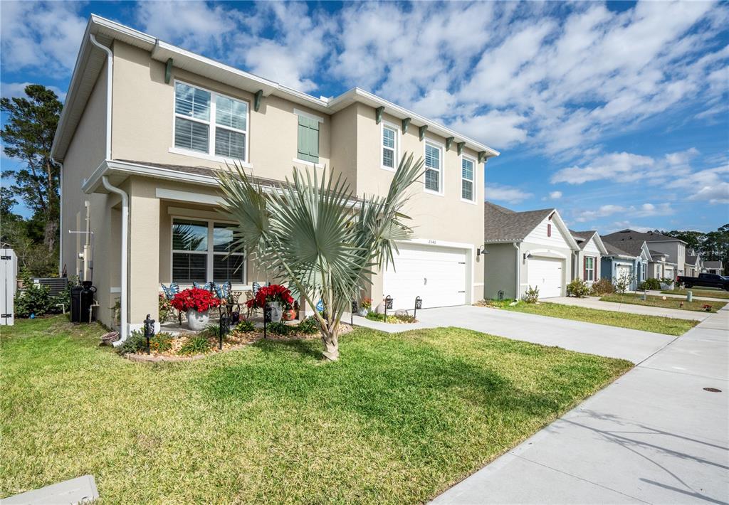 A two-story suburban house with a palm tree in the front yard and a driveway — 2540 HARMONIA HAMMOCK ROAD, HARMONY, FL