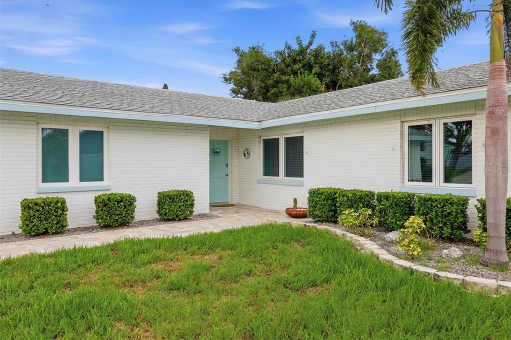 A white brick single-story house with a light blue front door and a palm tree — 6309 FLAMINGO DRIVE, APOLLO BEACH, FL