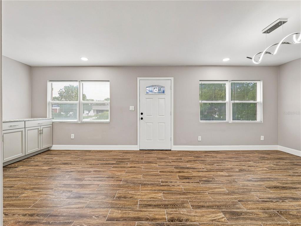 A room with wood-look tile flooring, light gray walls, a white front door, and cabinetry — 629 CEDAR PARK DRIVE, DAYTONA BEACH, FL