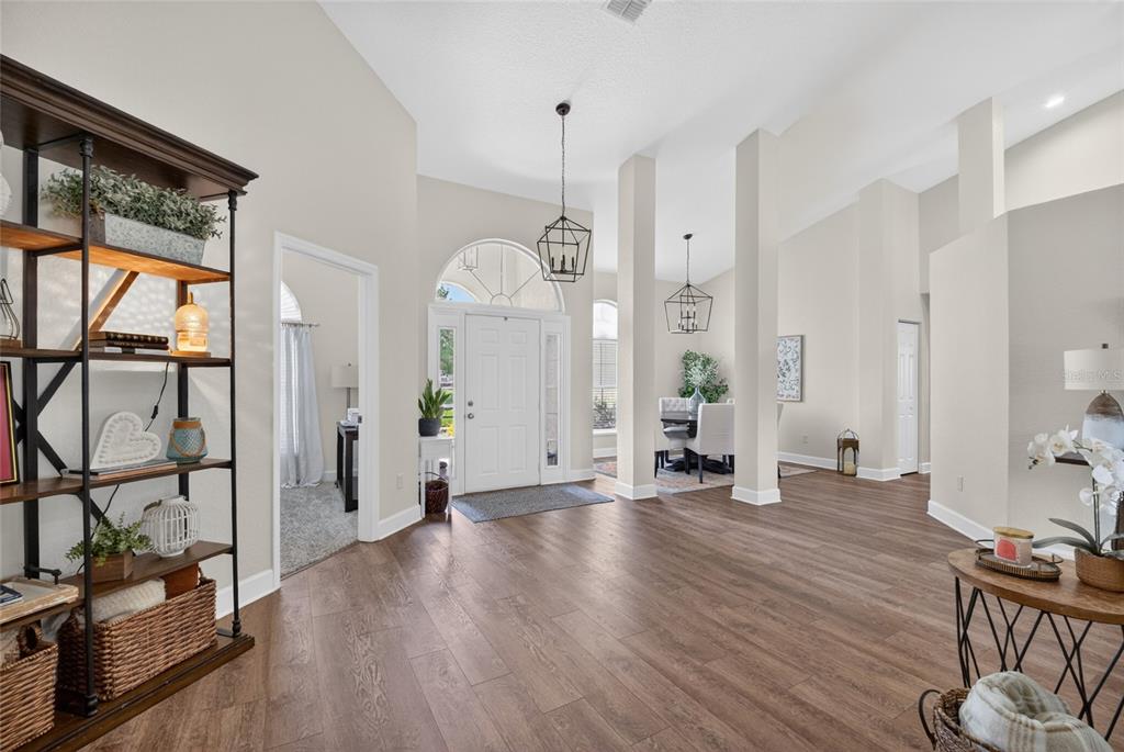 A bright foyer with wood-look flooring, high ceilings, and a view into the dining area — 3903 SE 38TH LOOP, OCALA, FL