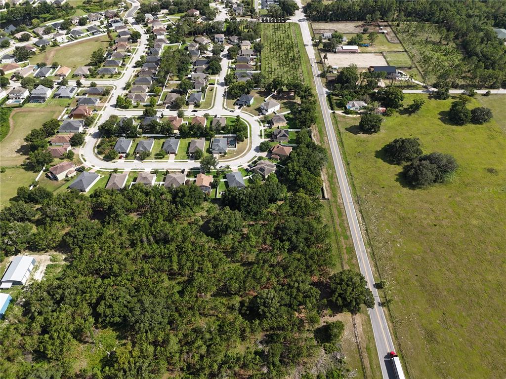 An aerial view shows a suburban neighborhood adjacent to a rural road and fields — 00 E COUNTY ROAD 44, EUSTIS, FL