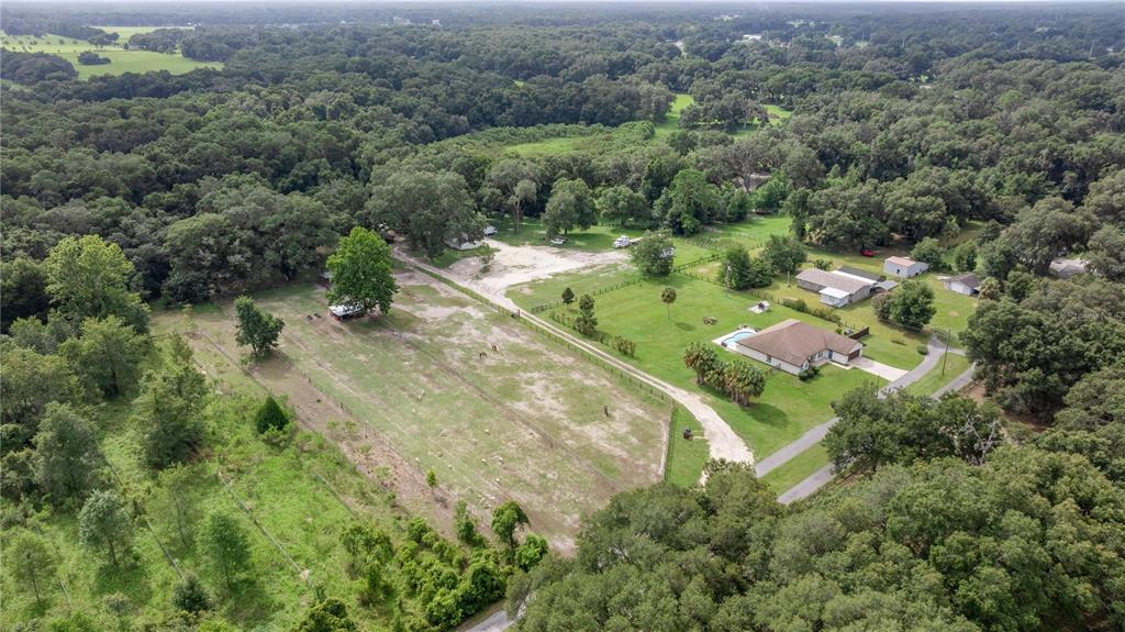 An aerial view shows a rural property with a house, pool, pasture, and surrounding trees — 13783 SE 8TH COURT, OCALA, FL