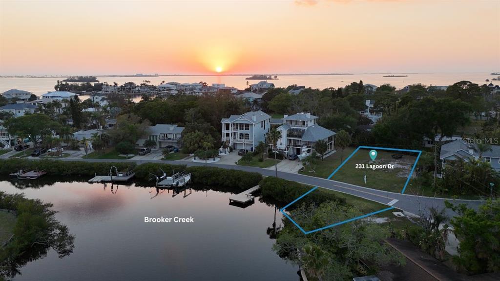 An aerial view shows a vacant waterfront lot outlined in blue along a residential street — 231 LAGOON DRIVE, PALM HARBOR, FL